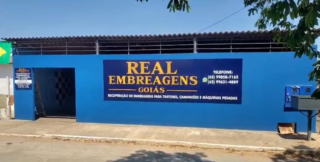 Fachada da Real Embreagens Goiás em Posse-GO: parede azul com placa REAL EMBREAGENS GOIÁS em letras douradas